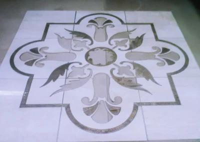 Elegant floral pattern inlaid into a tile floor, with a symmetrical design and muted colors