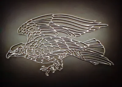 Metallic silhouette art of an eagle in flight against a dark background.